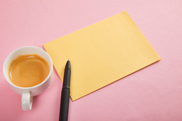 yellow envelope with pen and coffee cup on pink background