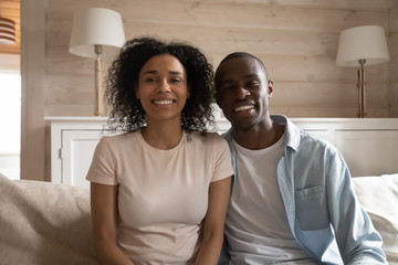 Obraz premium Smiling african couple sitting on couch making video call