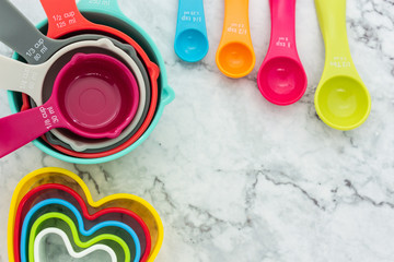 Set of measuring cups, measuring spoons and plastic cookie cutters use in cooking lay on marble...