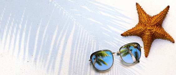 Summer concept, starfish shell and sunglasses on the tropical beach sand, with copy space