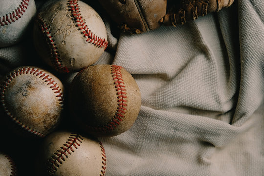 Old rough and rugged baseballs with used ball glove on canvas background for sports game concept.