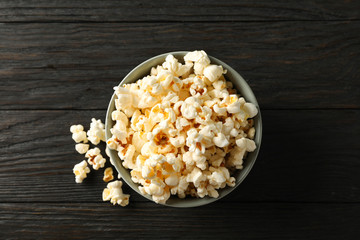 Bowl with popcorn on wooden background, space for text