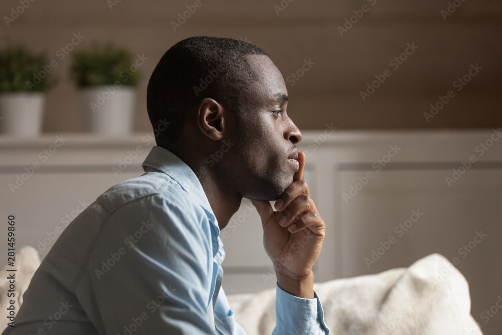 Wall mural Profile face of sad african guy thinking indoors