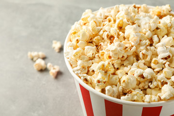 Bucket with popcorn on grey background, space for text