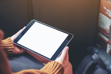 Mockup image of a woman sitting and holding black tablet pc with blank white desktop screen
