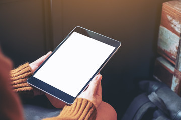 Mockup image of a woman sitting and holding black tablet pc with blank white desktop screen