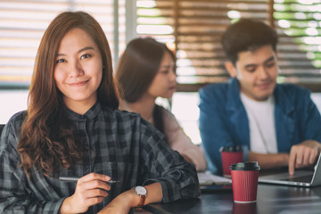 A beautiful asian businesswoman with colleaque working on laptop in background