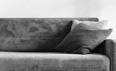 Grey sofa with two cushions on white wall background