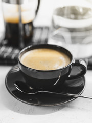 Coffee in black Cup on white background, table. French press,carafe of water, napkin, sunlight. Breakfast.