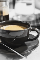 Coffee in black Cup on white background, table. French press,carafe of water, napkin, sunlight. Breakfast.