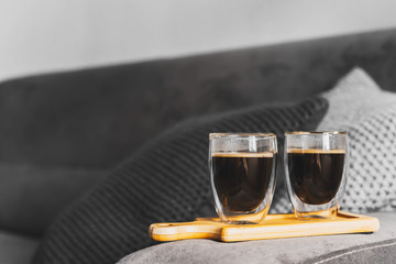Two cups of espresso on a wooden tray, on the sofa in a cozy home environment