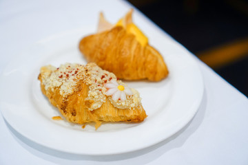 Breakfast of Fresh croissant with ham, cheese and jam on white plate on white table