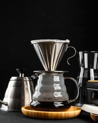 Alternative coffee brewing method,pure over,glass teapot on wooden tray with freshly brewed coffee on dark background.