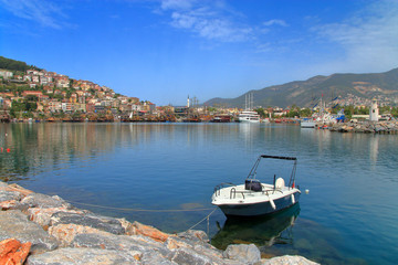 Landscape of the promenade of the city of Alanya with a lonely boat in the foreground.