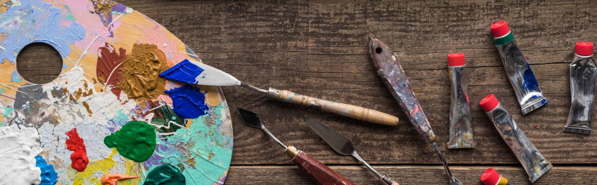 top view of colorful paints and drawing tools on wooden surface, panoramic shot