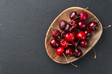 Cherry on a wooden plate on a dark background