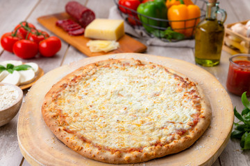 Delicious fresh out of over cheese pizza on wooden board surrounded by organic ingredients