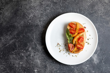 Bruschetta with tomatoes on a white plate against dark background. Top view, copy spase