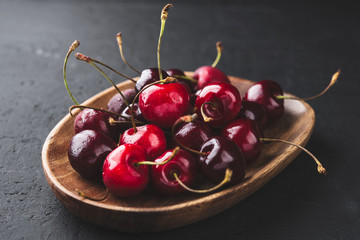 Cherry on a wooden plate on a dark background