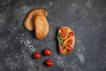 Bruschetta with tomatoes in the hands on a dark background, top view.