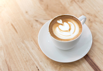 Hot coffee cappuccino in white coupon wooden table.