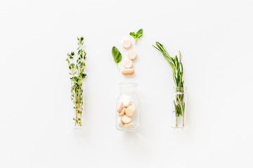 Homeopathy with pills, leaves and healing herbs on white background top view