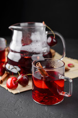 Freshly brewed tea with cherries on a dark concrete background