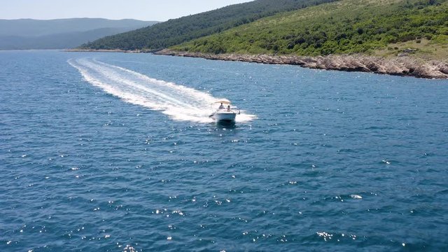 Aerial Dolly front view of speedboat cruising high speed in Adriatic Sea. Drone Flying over crystal clear water, Beautiful Couple drive small luxury boat sailing Mediterranean Sea.