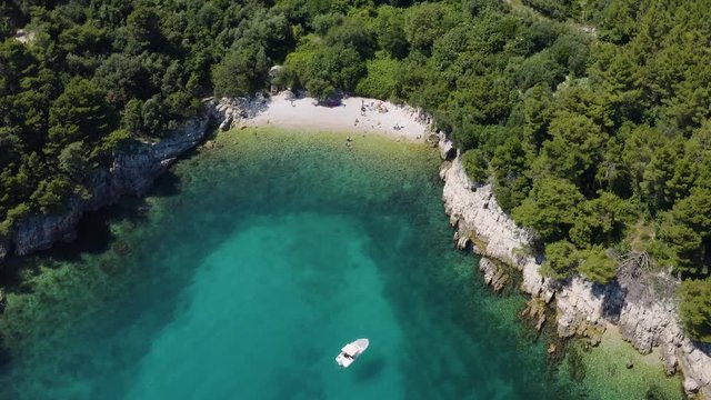 Aerial view of Hidden sand beach in Rabac, Croatia. Yacht moored on crystal clear water of Mediterraean sea. Unspoiled Nature and cliffs.