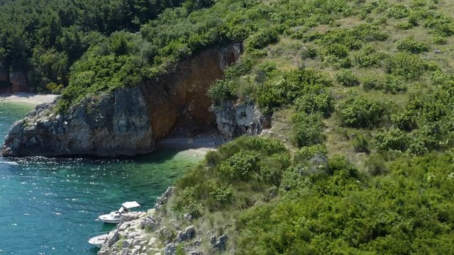 Great Aerial view of Hidden Beach with small modern luxury boat in Rabac, Croatia. Flying over mediterranean coastline cliff with white sand and turquoise sea.  Croatian Secluded Bay.