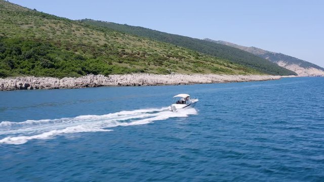 Aerial Panoramic Tracking  speedboat sailing in Adriatic Sea. Drone Following Luxury small boat cruising crystal water. Mediterranean paradise with green hills and lush nature In Rabac, Croatia.