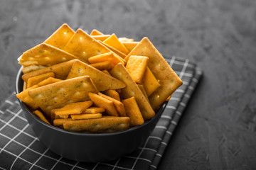 Black bowl with crackers on a dark concrete background