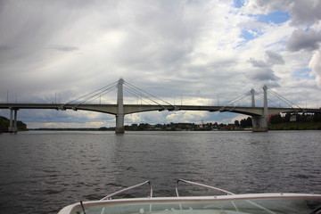 Large bridge across the Volga river in the city of Kimry the Tver region on a summer day on the background of a stormy sky with clouds, view from bow of white motor boat