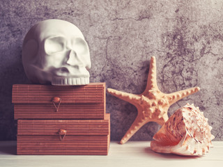 The decorative figure in the form of a human skull is on wooden caskets. Nearby are seashell and a...