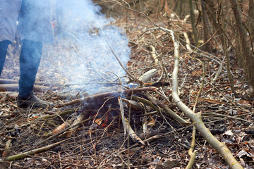 Man makes bonfire in the autumn forest