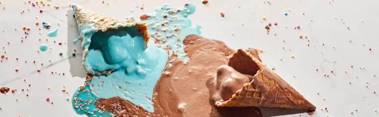 delicious melted chocolate and blue ice cream in waffle cones on marble grey background with sprinkles, panoramic shot