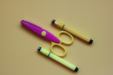 Two Yellow markers and the scissors on a yellow background