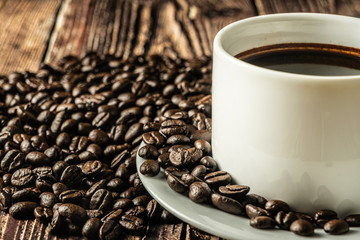 a cup of coffee with coffee beans on the rusty wooden table