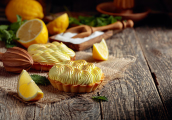 Tartlets with lemon cream and mint on a old wooden table.