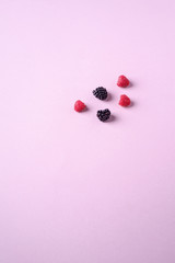 Raspberry and blackberry sweet organic juicy five berries on pink paper background, copy space