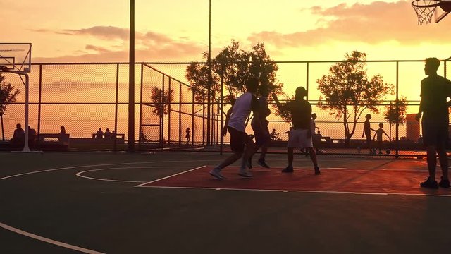Sunset Basketball Game captures a group of young men playing basketball at sunset, creating a silhouette look.                                                                                          