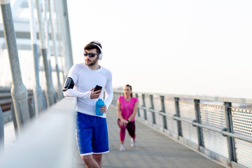 Obraz premium Couple exercise on the bridge at the end of day with headphones on head