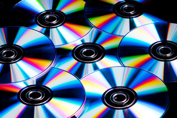 a collection of cd, dvd disks with rainbow colour reflections