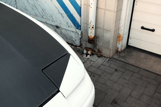 Weißer japanischer Sportwagen der Neunzigerjahre mit Motorhaube in Mattschwarz und Klappscheinwerfer vor einer Werkstatt in Wettenberg Krofdorf-Gleiberg bei Gießen in Hessen