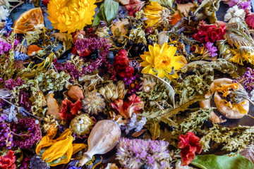 A colorful closeup of dried flowers, dried oranges, fragrant herb leaves, and seedpods used as...