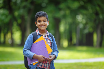 Outdoor portrait afro american happy school boy with books and backpack. Young student beginning of class after vacation. Back to school concept.