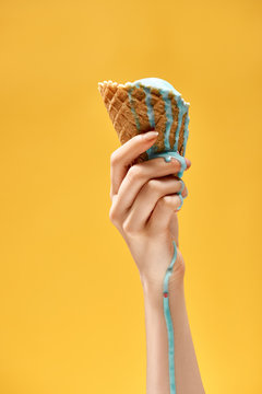 cropped view of woman holding delicious melted blue ice cream in crispy waffle cone isolated on yellow