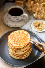 Pancakes with banana, nuts and honey, served with tea. Rustic style.