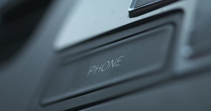 Finger pushing the phone bluetooth button on a car dash