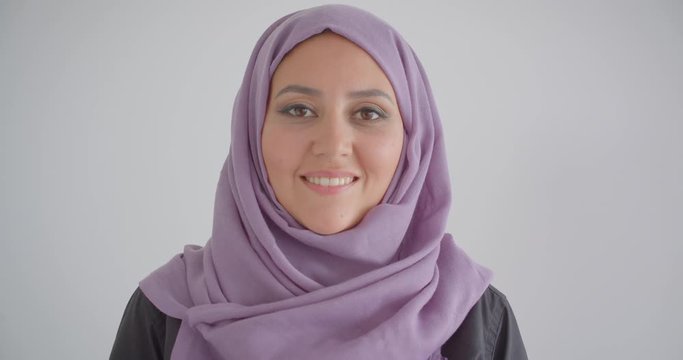 Closeup portrait of young pretty muslim woman in hijab looking at camera smiling cheerfully with background isolated in white
